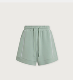 A pair of sage green athletic shorts with a drawstring waist and white piping details, shown against a light gray background.