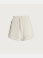 A pair of cream-colored high-waisted shorts with an elastic waistband and a matching drawstring, shown against a solid off-white background.